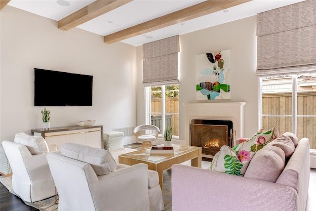 living room with visible vents, beam ceiling, and a lit fireplace