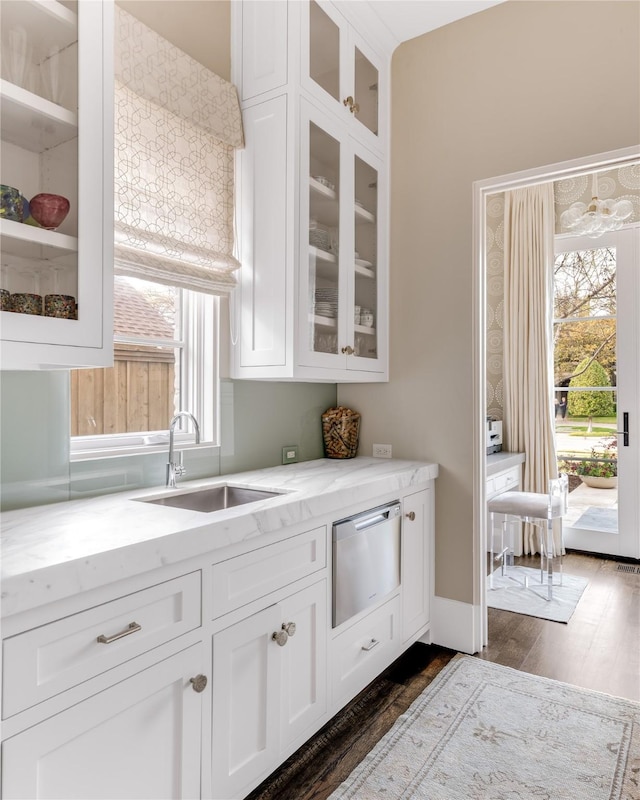 kitchen with a warming drawer, light stone counters, a wealth of natural light, and a sink