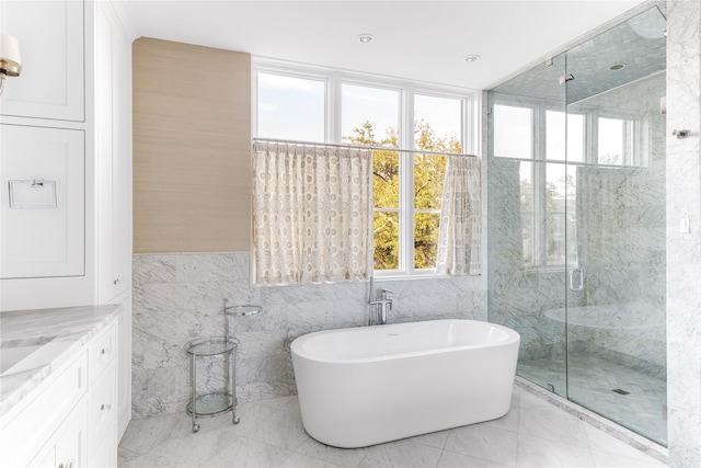 full bath featuring a wealth of natural light, a marble finish shower, marble finish floor, and a freestanding tub