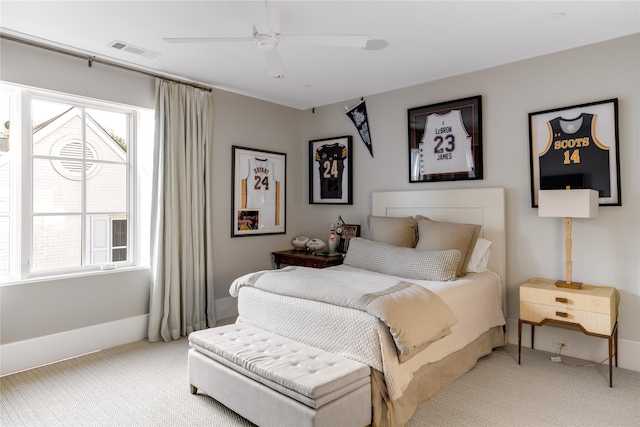 bedroom featuring baseboards, light colored carpet, visible vents, and ceiling fan