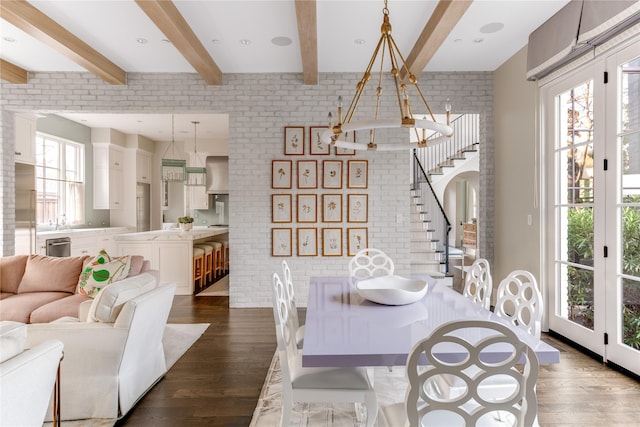 dining area with stairs, beamed ceiling, dark wood-style floors, and brick wall