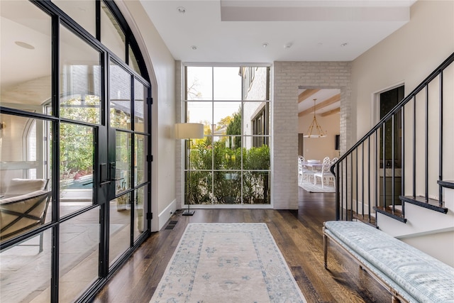 doorway with stairs, floor to ceiling windows, wood finished floors, and a wealth of natural light