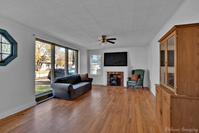 interior space with ornamental molding, a ceiling fan, baseboards, and wood finished floors