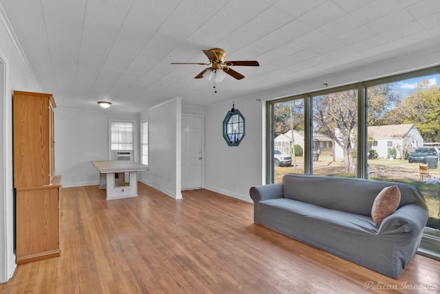 unfurnished room featuring baseboards, a ceiling fan, light wood-style flooring, and crown molding