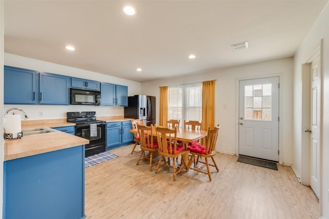 kitchen featuring blue cabinetry, light wood-style flooring, a sink, black appliances, and light countertops