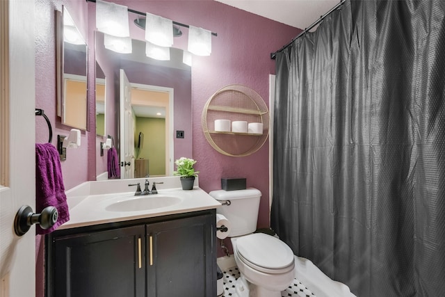 full bathroom featuring curtained shower, toilet, vanity, and a textured wall