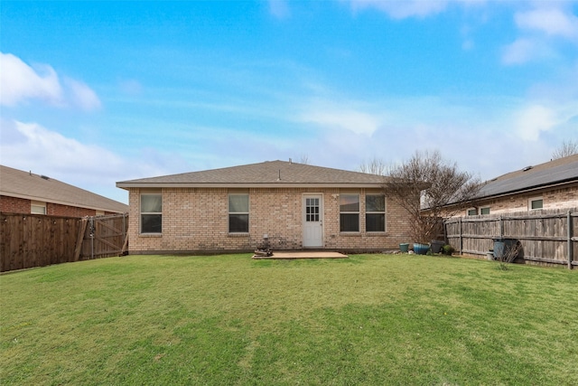 back of property featuring a yard, a patio, brick siding, and a fenced backyard