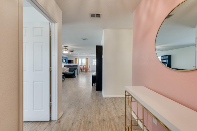 corridor featuring visible vents, baseboards, and light wood-style flooring