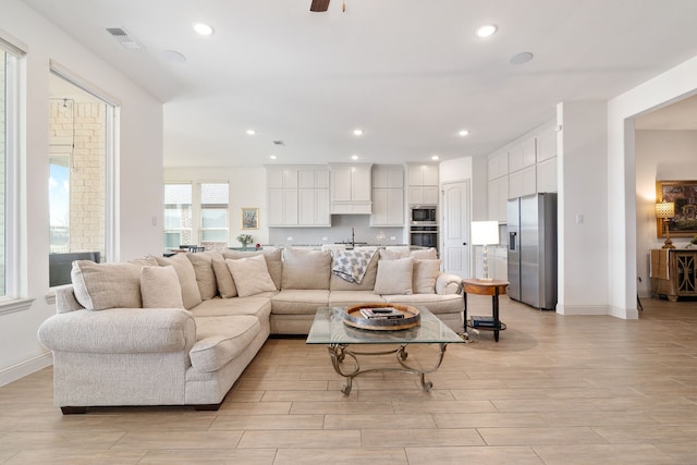 living room with recessed lighting, visible vents, baseboards, and light wood-style flooring