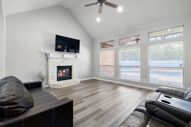 living area with wood finished floors, baseboards, high vaulted ceiling, a fireplace, and ceiling fan