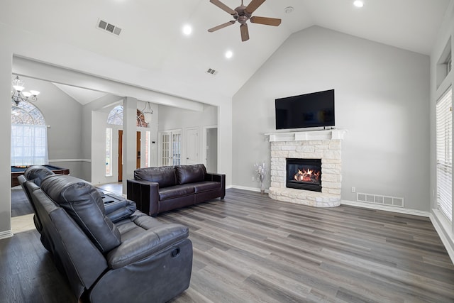 living room with a stone fireplace, a healthy amount of sunlight, visible vents, and high vaulted ceiling