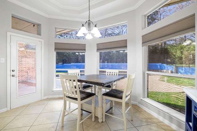 sunroom / solarium featuring a healthy amount of sunlight, a raised ceiling, and an inviting chandelier