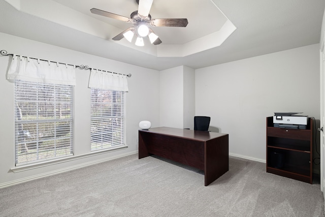 carpeted office with a tray ceiling, baseboards, and ceiling fan