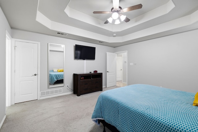 bedroom featuring a raised ceiling, carpet, visible vents, and ceiling fan