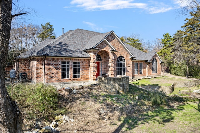 view of front facade featuring brick siding, a shingled roof, and a front lawn