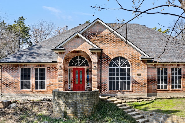 view of front facade with brick siding and a shingled roof