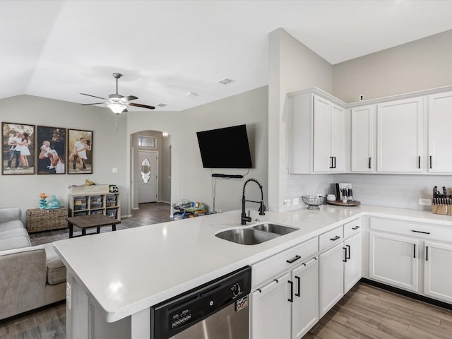 kitchen featuring a peninsula, arched walkways, a sink, stainless steel dishwasher, and open floor plan