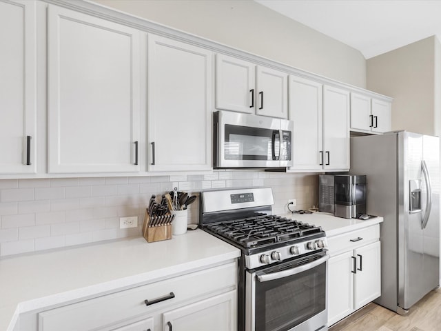 kitchen with light wood finished floors, light countertops, decorative backsplash, appliances with stainless steel finishes, and white cabinets