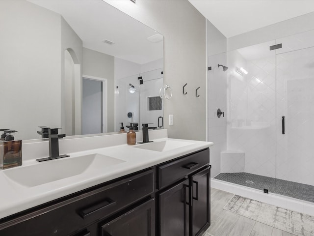 full bath with a sink, a stall shower, and double vanity