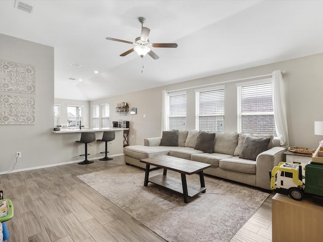 living area featuring a wealth of natural light, visible vents, lofted ceiling, and wood finished floors