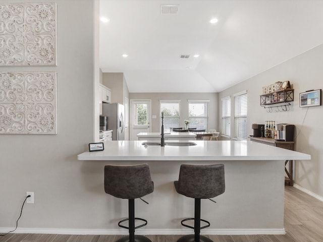 14556 Serrano Ridge Rd, Fort Worth, TX 76052 - kitchen featuring freestanding refrigerator, a sink, a breakfast bar, light countertops, and light wood-style floors