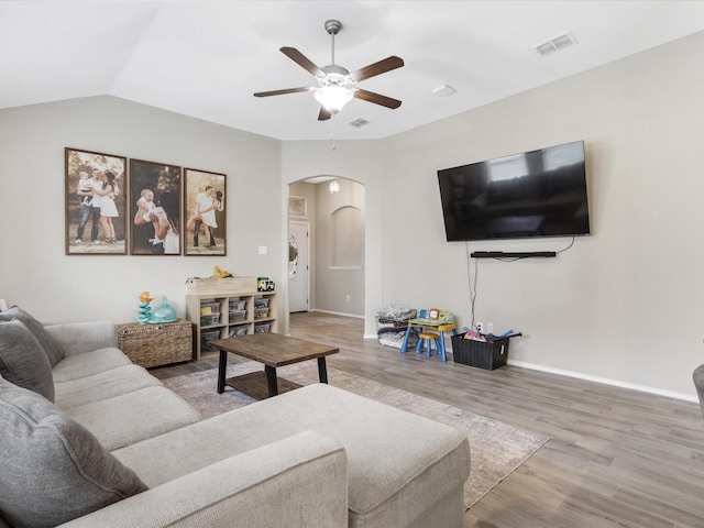 living room with visible vents, ceiling fan, vaulted ceiling, wood finished floors, and arched walkways