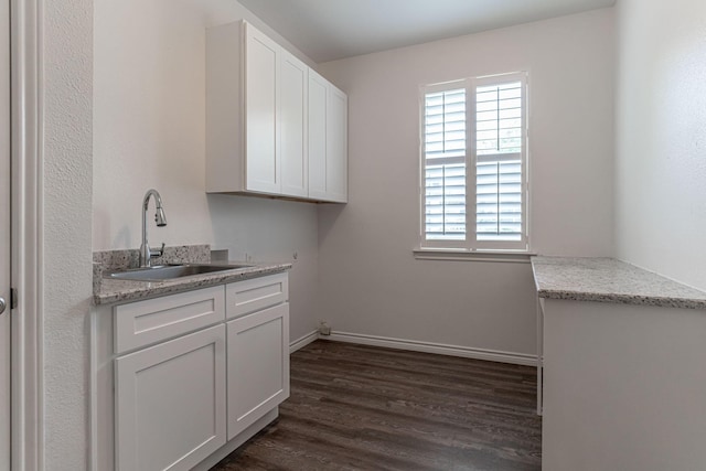 washroom with hookup for a washing machine, baseboards, cabinet space, a sink, and dark wood-type flooring