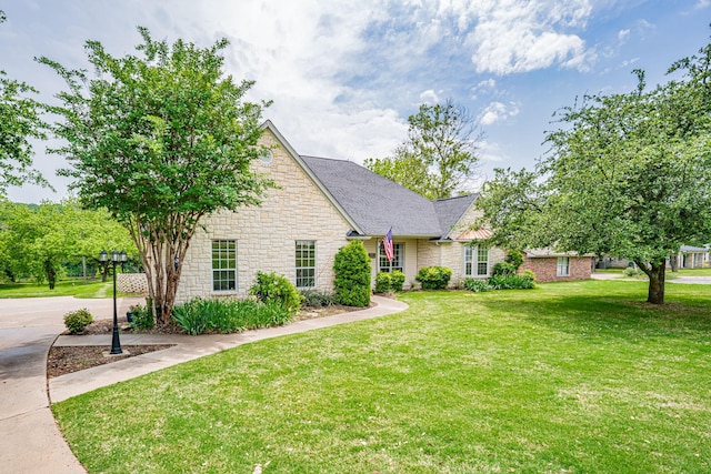 view of front of house featuring stone siding, a front lawn, and a shingled roof