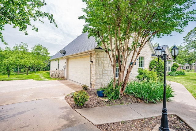 view of property exterior featuring stone siding, driveway, a shingled roof, and a yard