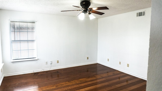 spare room featuring visible vents, a ceiling fan, a textured ceiling, dark wood-style floors, and baseboards