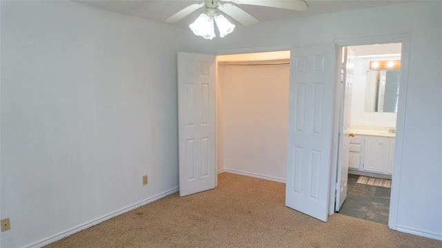 unfurnished bedroom featuring a ceiling fan, baseboards, a closet, light colored carpet, and connected bathroom