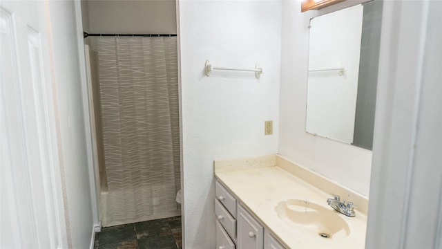 full bathroom featuring stone finish floor, vanity, a shower with shower curtain, and toilet