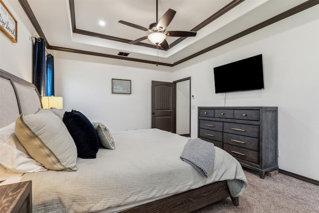 carpeted bedroom featuring visible vents, baseboards, a tray ceiling, ornamental molding, and a ceiling fan