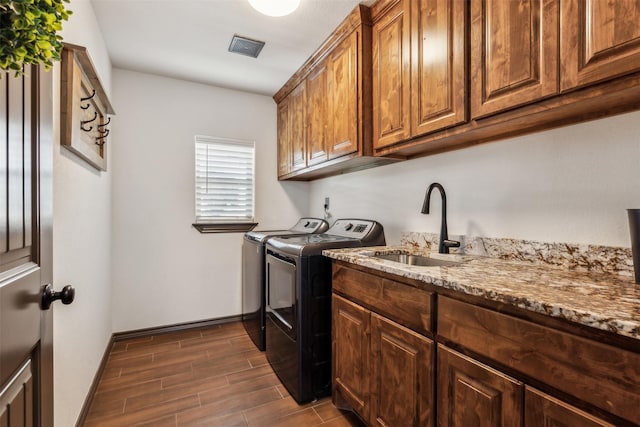 laundry room with visible vents, wood tiled floor, cabinet space, a sink, and independent washer and dryer