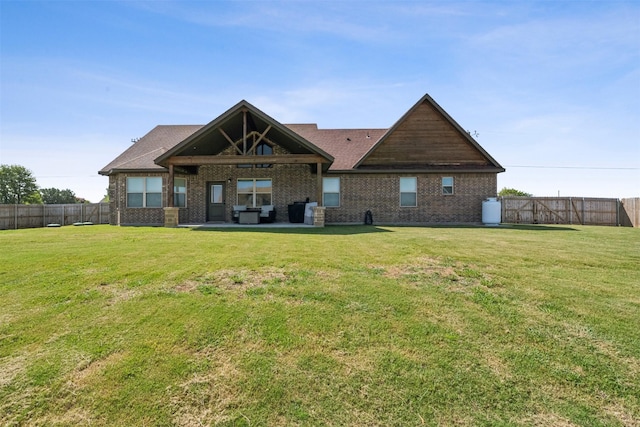 back of house with a fenced backyard, a patio, brick siding, and a yard