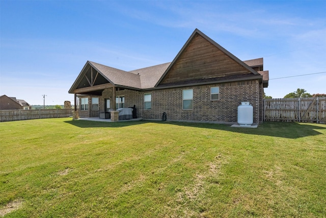 back of house featuring a patio, a lawn, a fenced backyard, and brick siding