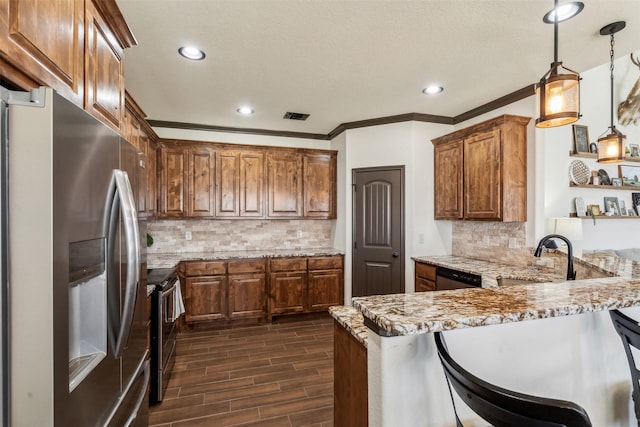 kitchen featuring wood finish floors, visible vents, a kitchen breakfast bar, appliances with stainless steel finishes, and a peninsula