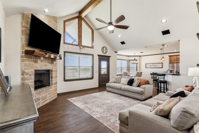 living area with visible vents, high vaulted ceiling, a stone fireplace, dark wood-type flooring, and ceiling fan with notable chandelier