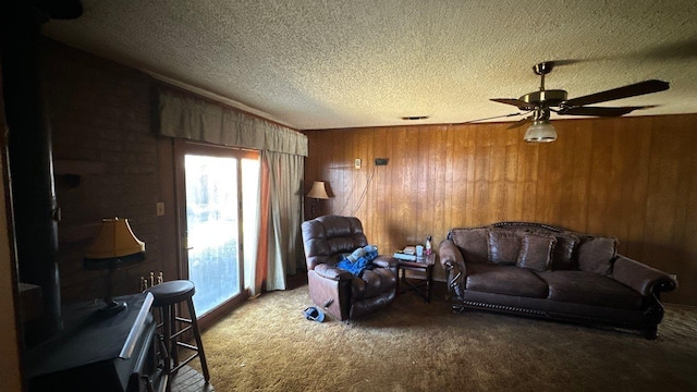 living area featuring wooden walls, a ceiling fan, carpet, visible vents, and a textured ceiling