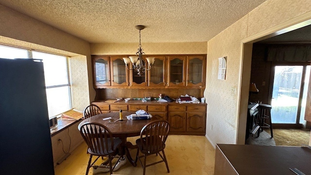 dining room with a textured wall, a notable chandelier, and a textured ceiling