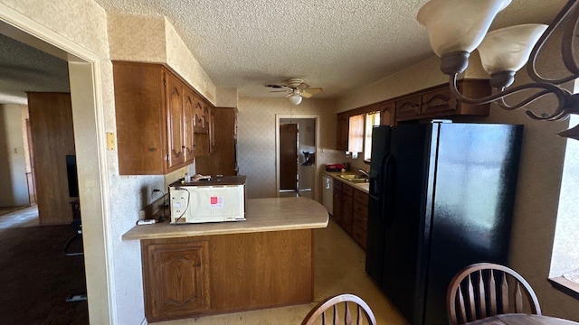 kitchen with a ceiling fan, a sink, a textured ceiling, black fridge with ice dispenser, and light countertops