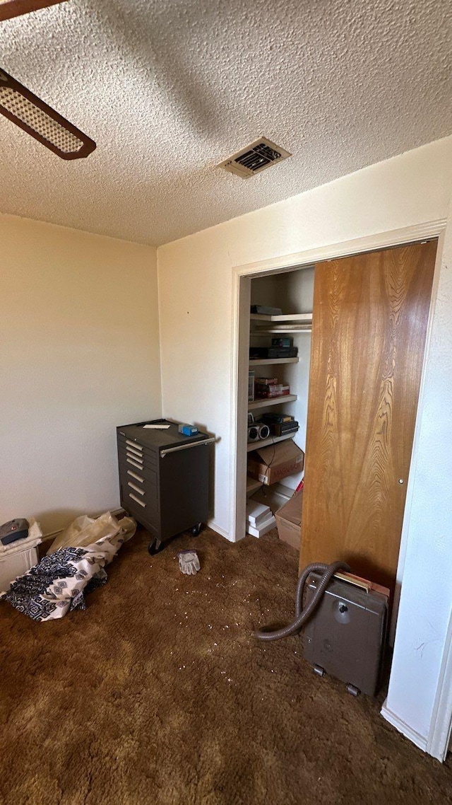 unfurnished bedroom with visible vents, a textured ceiling, a closet, and carpet