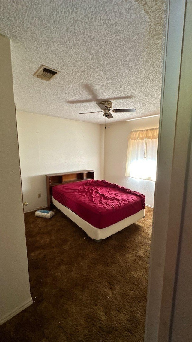 bedroom featuring ceiling fan, carpet flooring, visible vents, and a textured ceiling