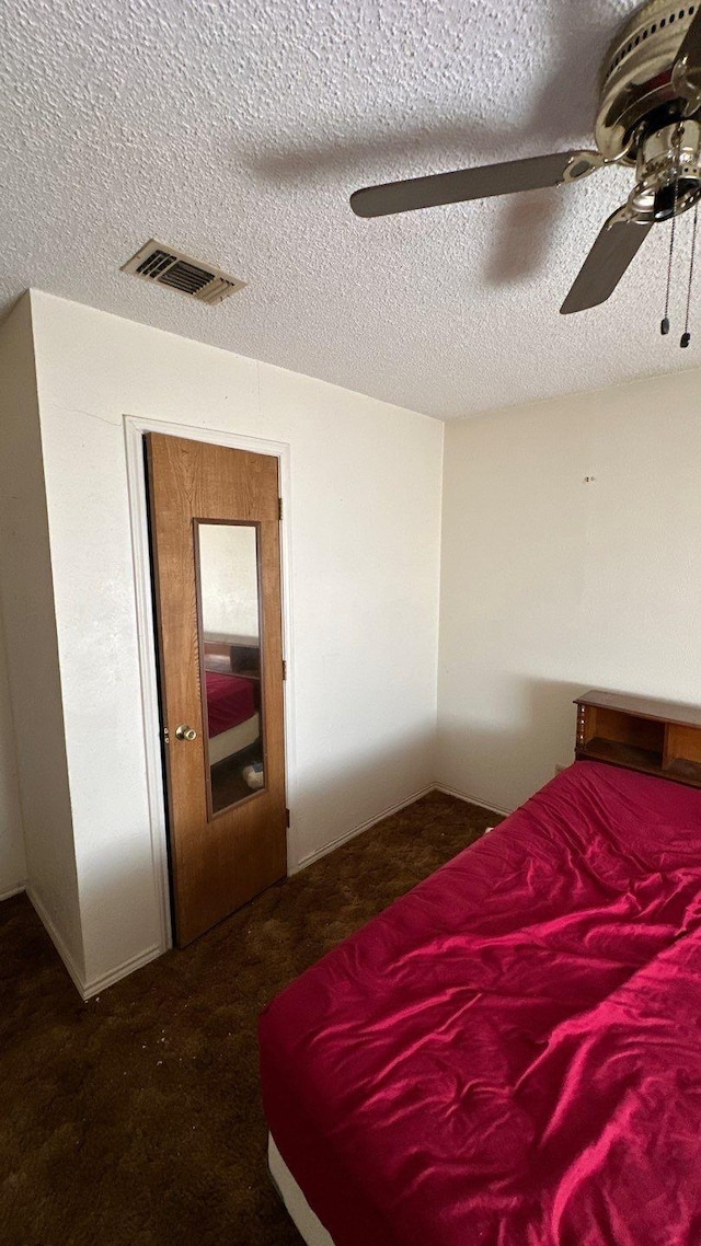 carpeted bedroom featuring visible vents, a textured ceiling, and a ceiling fan