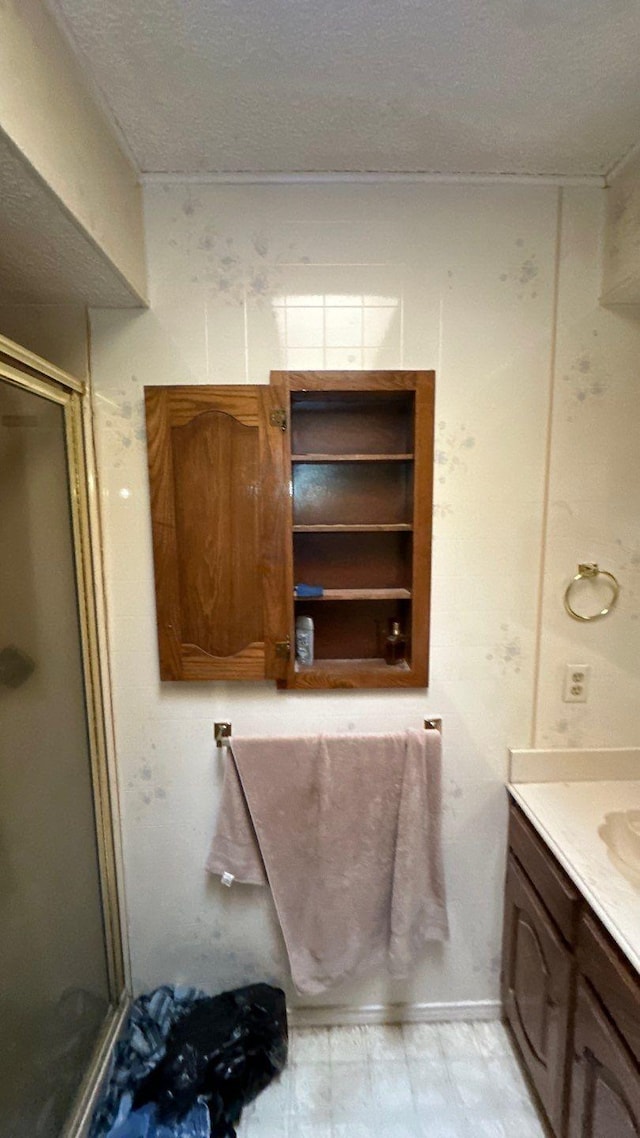 full bath featuring a textured ceiling, a stall shower, and vanity