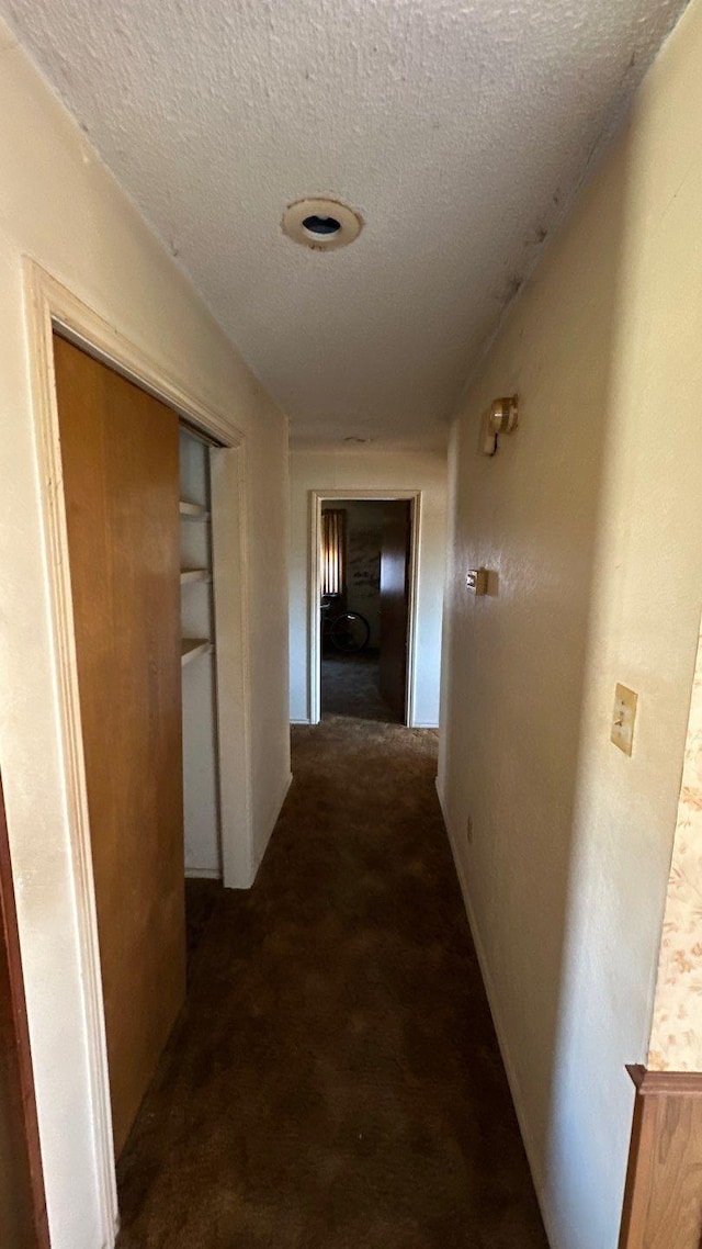 hall with a textured ceiling and carpet floors