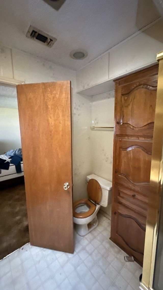 bathroom featuring tile patterned floors, visible vents, connected bathroom, and toilet