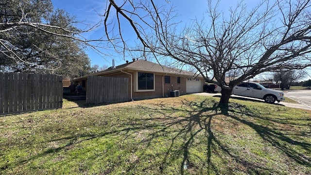 view of yard featuring central air condition unit, an attached garage, driveway, and fence