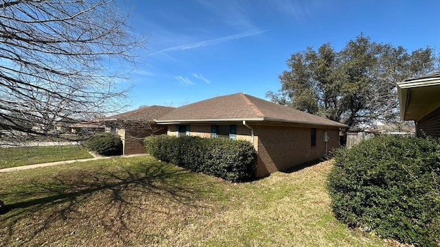 view of property exterior featuring brick siding and a yard