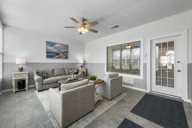 living room featuring tile patterned floors, visible vents, baseboards, and ceiling fan